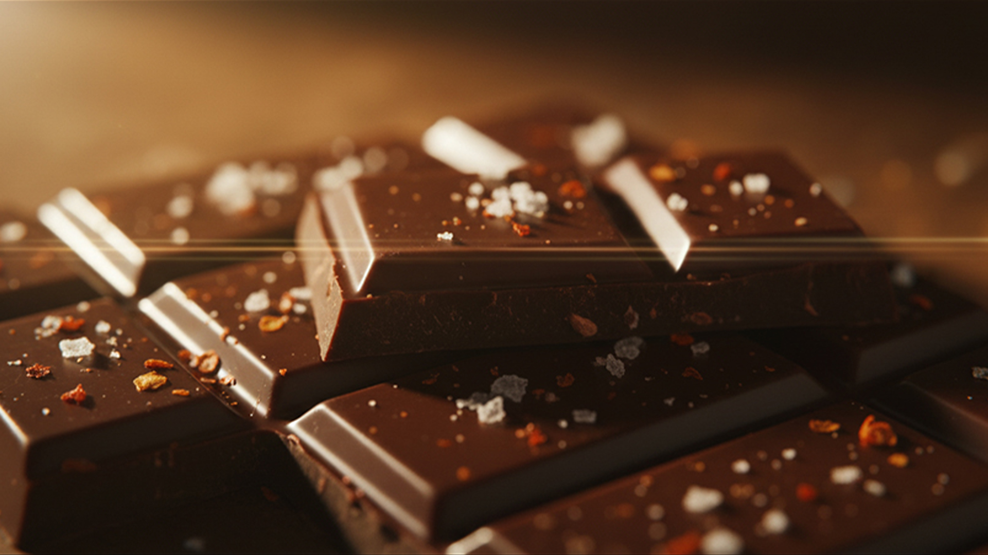 A cinematic macro shot of perfectly broken dark chocolate squares with flakes of sea salt.